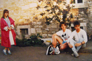 foto von drei jungen menschen, offensichtlich aus den achtzigern, links steht nele in einem leuchtend roten mantel, in der mitte sitzt „der pöhler“ in sportklamotten, rechts sitzte ich, felix