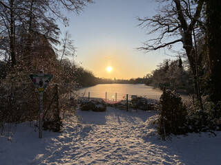 bild vom winterlichen, gefrorenem plötzensee, über dem see hängt die morgensonne