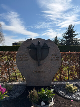 ein lächelnder jesus hängt an einem grabstein und trägt am rechten arm ein herz