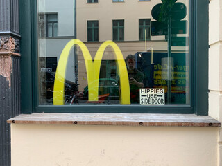 bild eines galerie schaufensters mit einem &bdquo;vintage&ldquo; mcdonalds M und einem fake &bdquo;HIPPIES USE SIDE DOOR&ldquo; schild