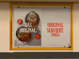 foto eines coca cola werbeplakats mit der aufschrift „das original“ und „original serviert“