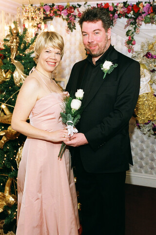 katia und ich in schick im kitsch, katia trägt ein rosa kleid und felix einen schwarzen anzug, wir haben beide weisse-rosen-gestecke