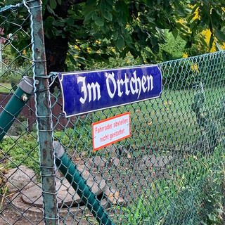 foto eines strassenschildes in einer gartensiedlung auf dem steht &bdquo;im &ouml;rtchen&ldquo;. dadrunter ein schild mit der aufschrift &bdquo;fahrr&auml;der abstellen nicht gestattet&ldquo;.